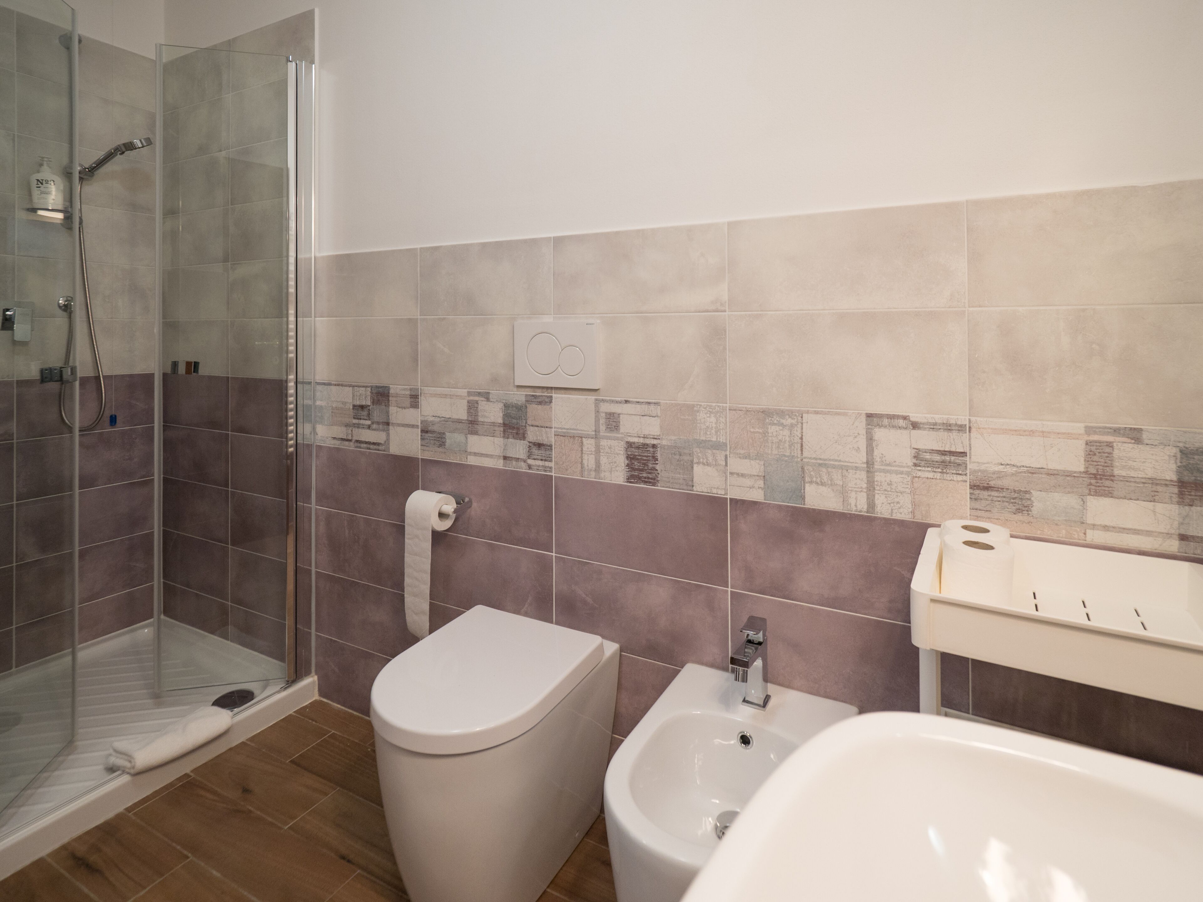 Ein modernes Badezimmer mit Duschkabine aus Glas, Toilette, Bidet und Waschbecken.