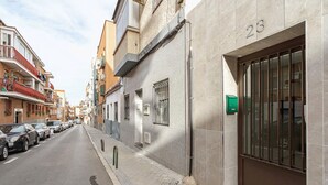 A narrow urban street with parked cars, a building with a large glass door, and a visible apartment number 23. - Mad Apartments by Olala Homes (Madrid)