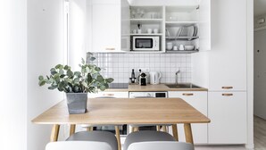 A modern kitchen with white cabinetry, a wooden table, and a potted plant. - Mad Apartments by Olala Homes (Madrid)