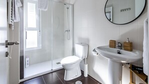 A modern bathroom with a glass-enclosed shower, a white toilet, and a sink with wooden soap dispensers. - Mad Apartments by Olala Homes (Madrid)