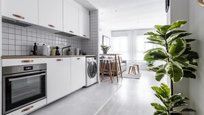 A modern kitchen with white cabinets, a built-in oven, and a washing machine. - Mad Apartments by Olala Homes (Madrid)