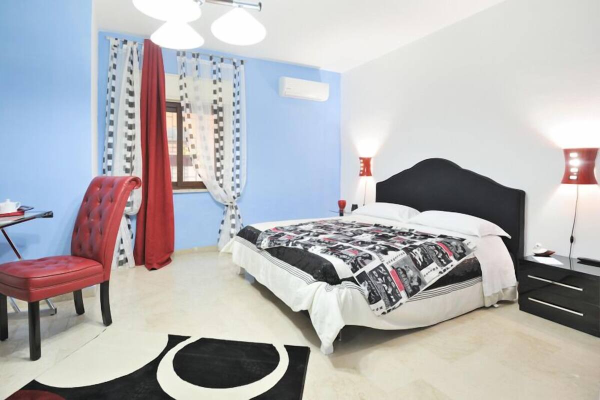 Un dormitorio con cama, silla, escritorio y lámpara.