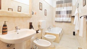 A bathroom with a large sink, a bidet, a bathtub, and a shower curtain. - La Casa Di Evita (Carini)
