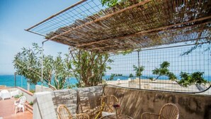 Um terraço com mobiliário de vime e vista para o oceano.