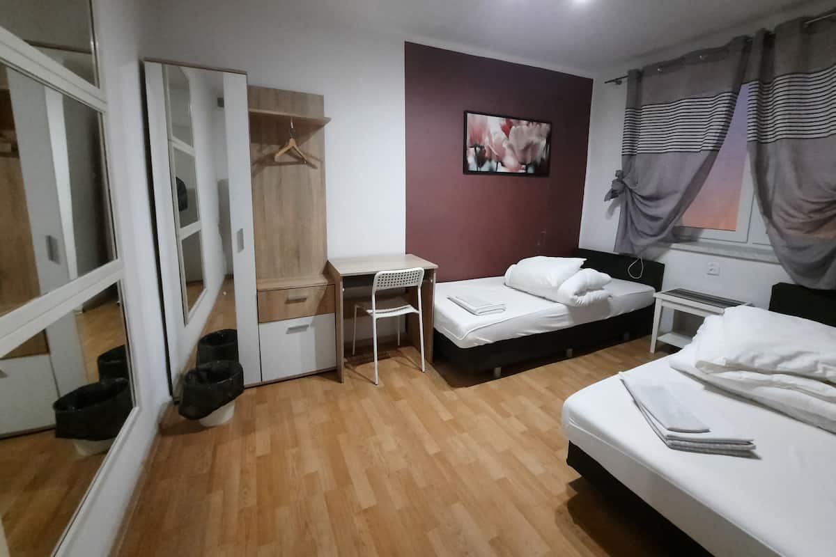 A bedroom with a bed, a desk, a wardrobe, and a mirror.