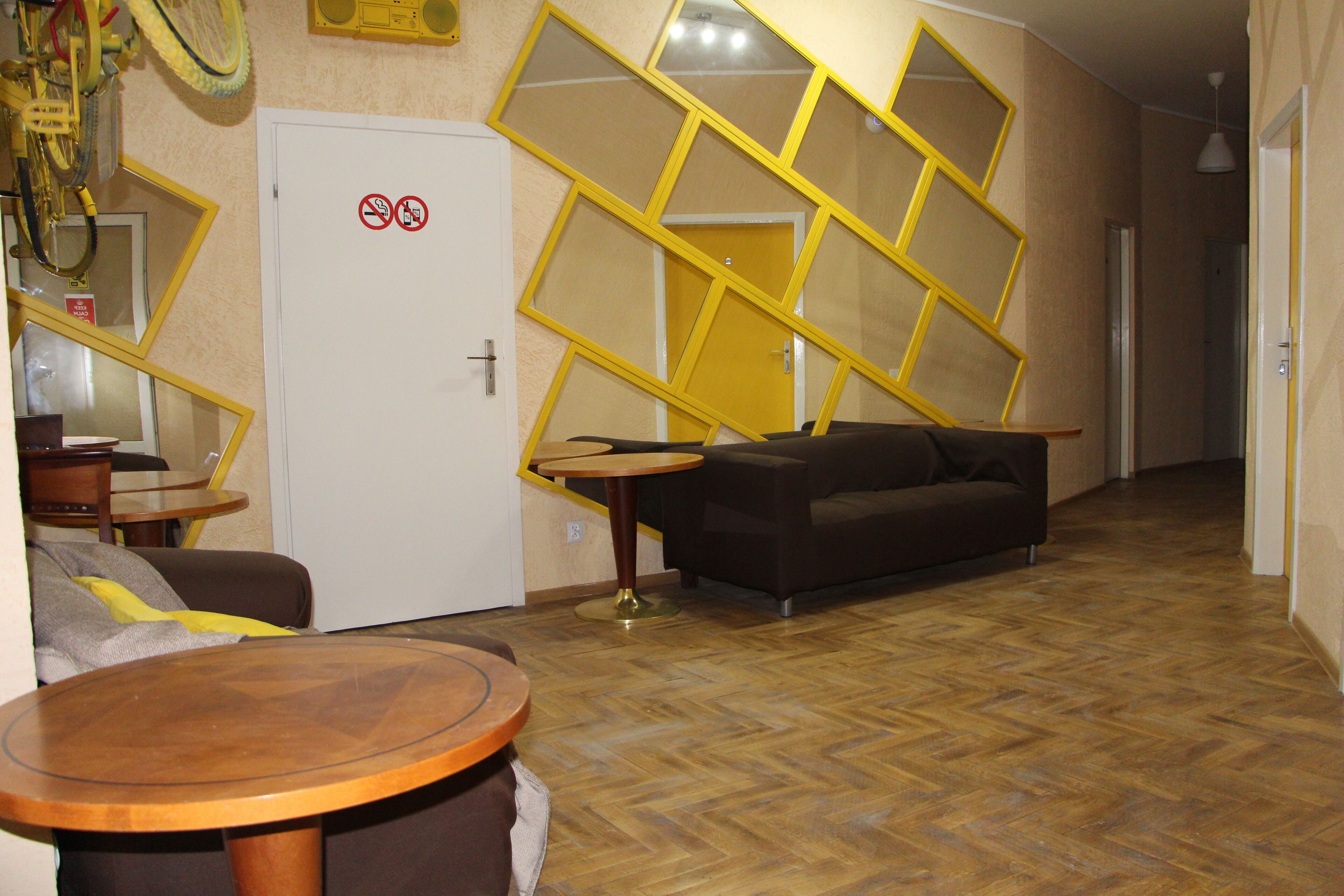 Una habitación con suelo de espiga, un sofá, una mesa redonda de madera y una puerta con un cartel de prohibido fumar.