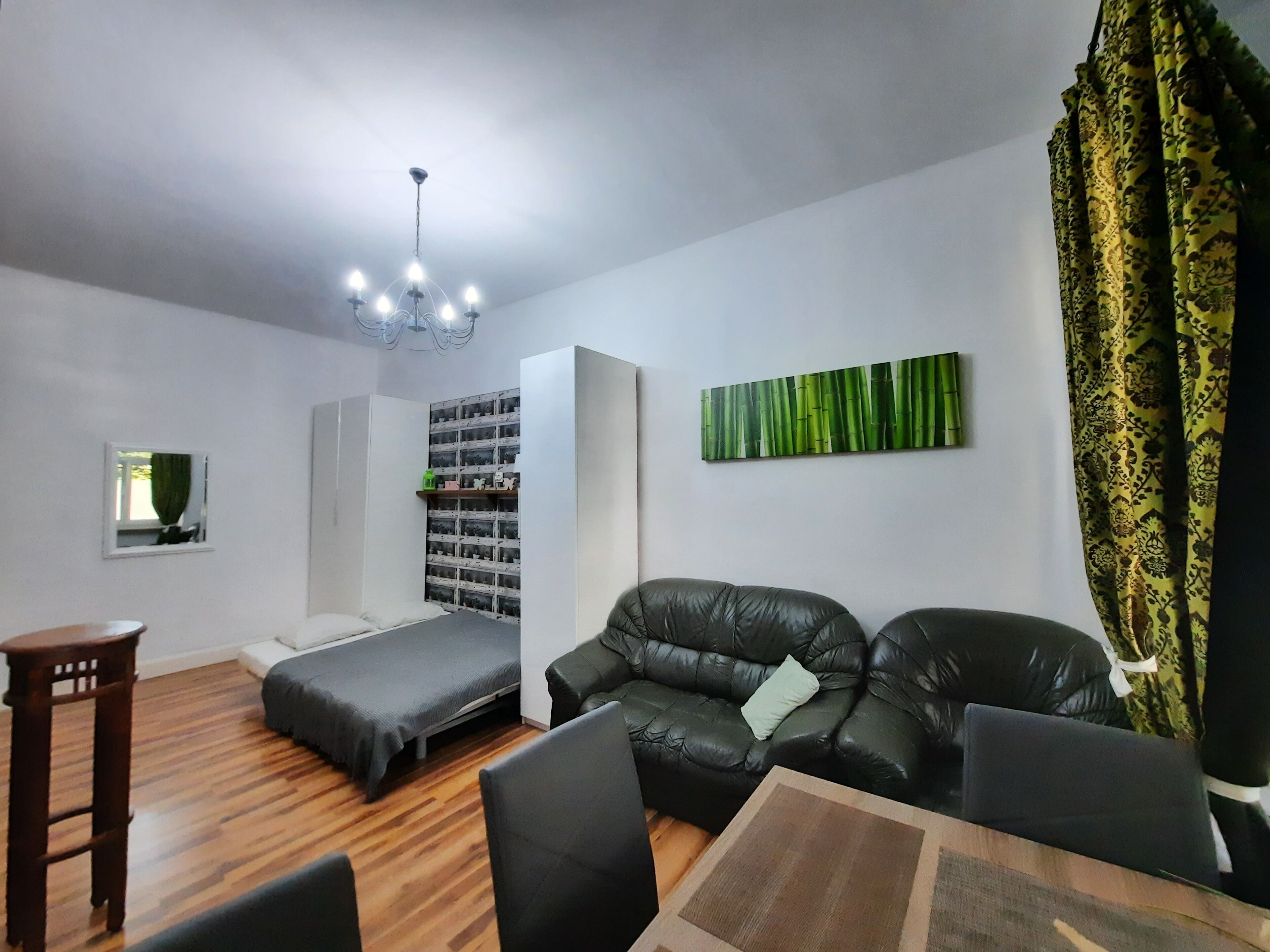 Um espaço compacto com cama, sofá, uma pequena mesa e estante.