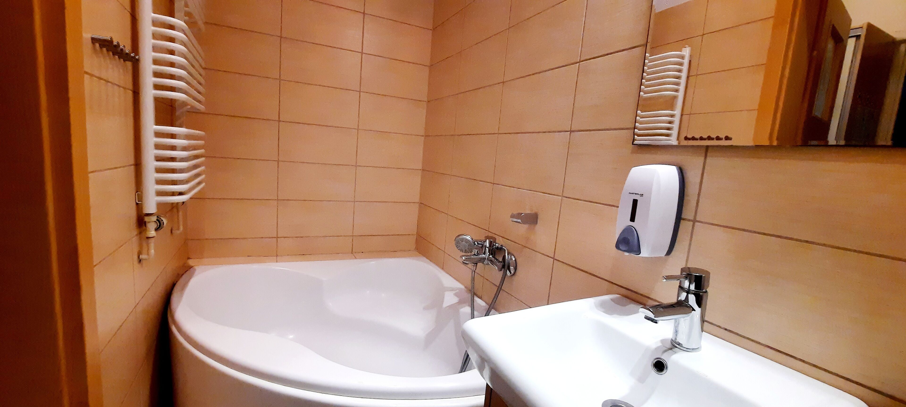 Un baño con bañera, lavamanos y secamanos.