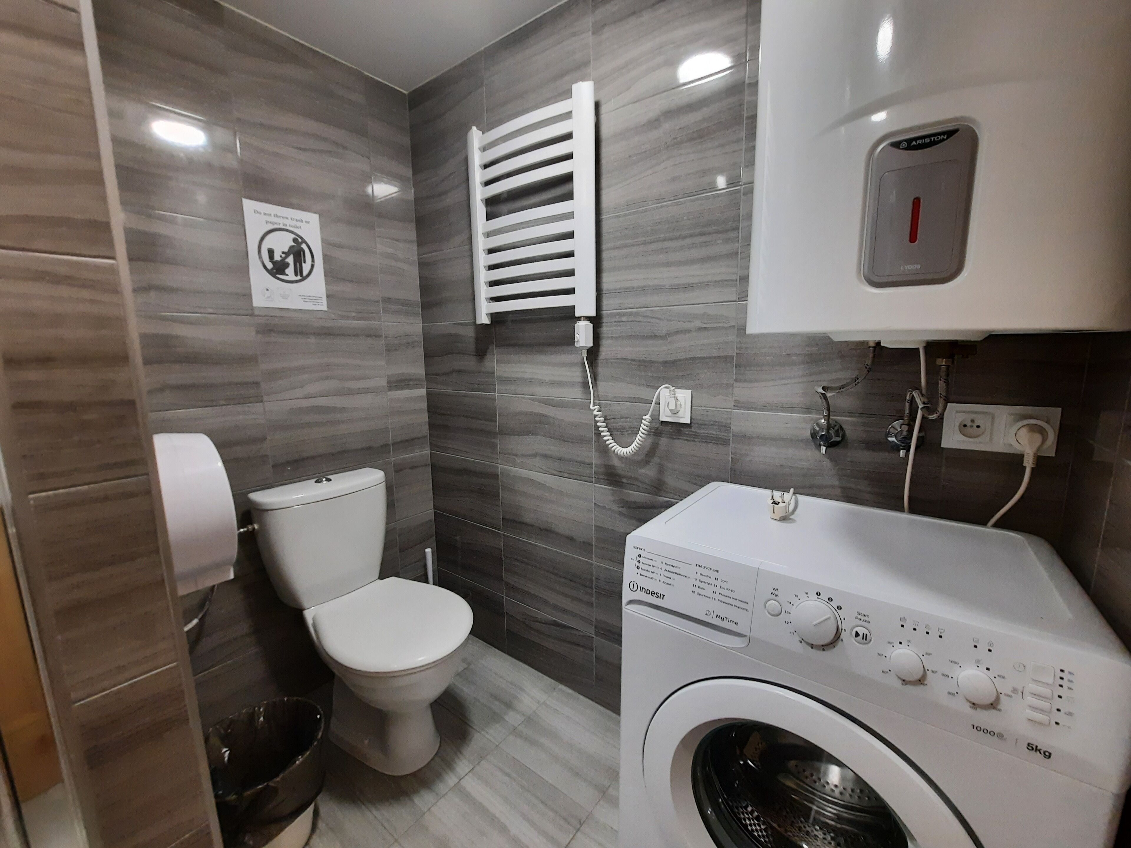 Uma casa de banho moderna com sanita, máquina de lavar roupa e barra de toalhas.