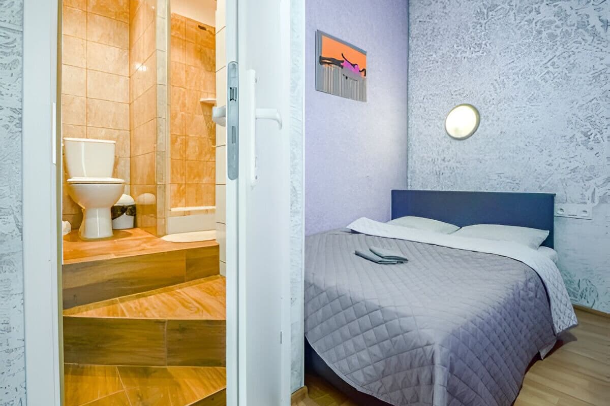 A bedroom with a bed, a nightstand, and a wall-mounted light fixture.