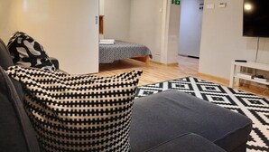 En moderne stue med sofa, mønstrede puder, seng med mønstret dynebetræk, et fladskærms-tv og et mønstret tæppe.
