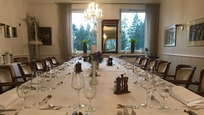 Ein formeller Speisesaal mit einem langen Tisch, gedeckt für eine Mahlzeit, umgeben von Stühlen.
