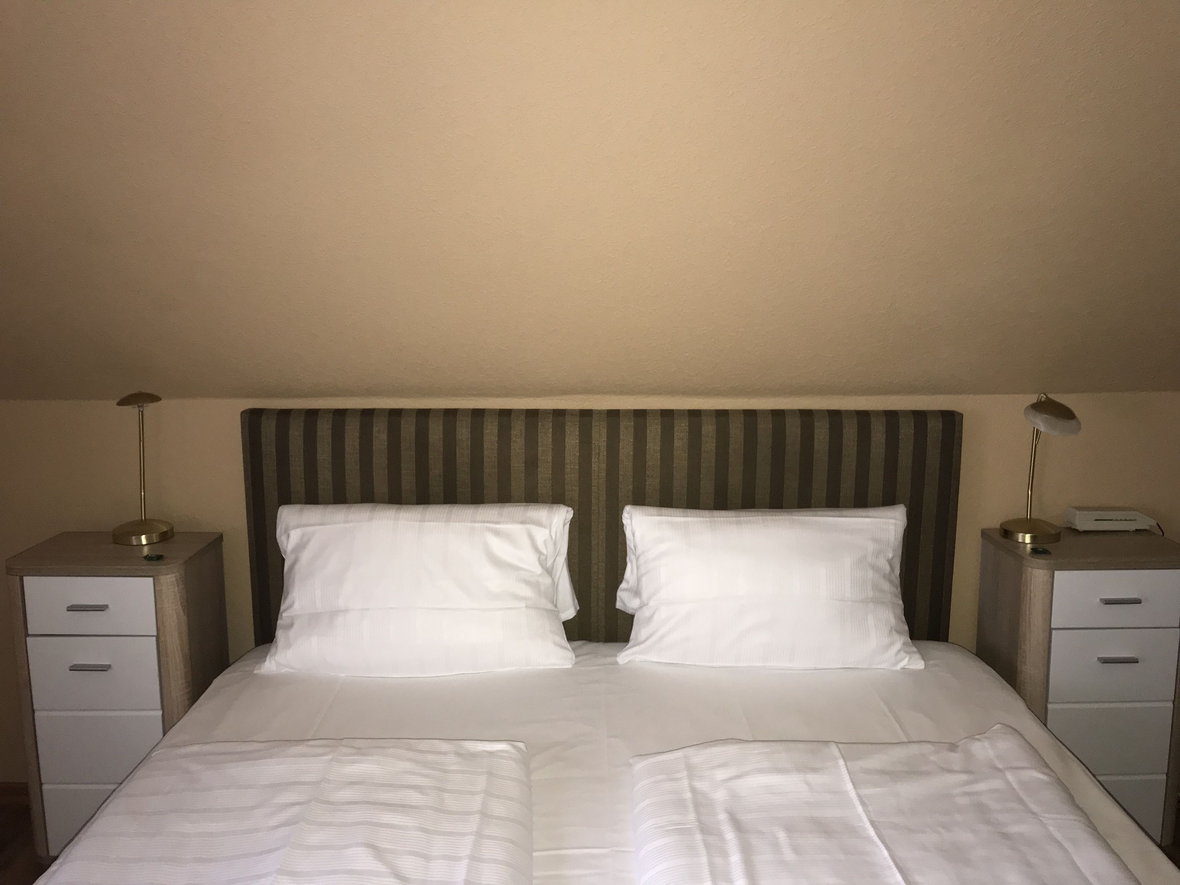 Una habitación de hotel con una cama grande, dos mesitas de noche y un cabecero a rayas.