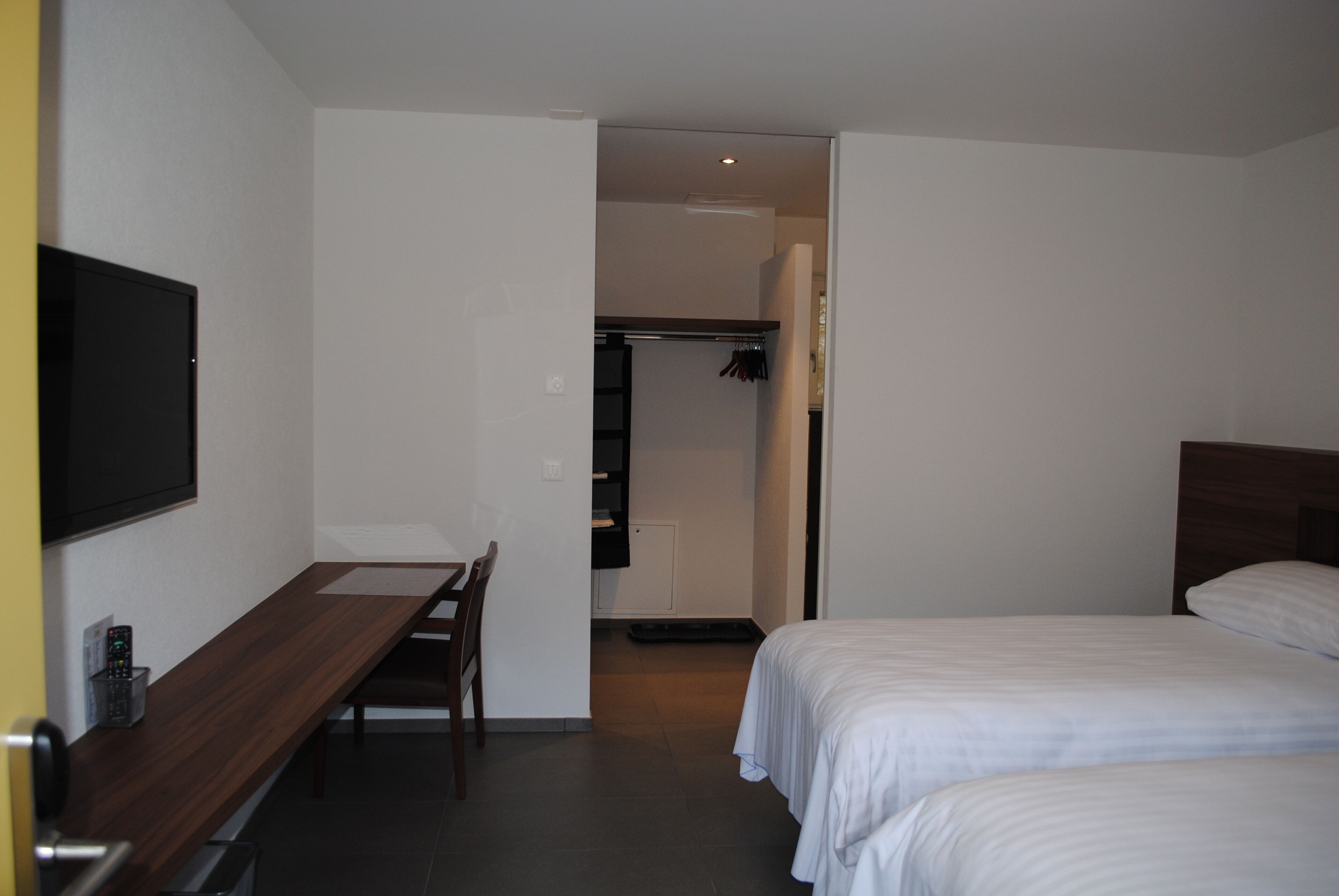 A hotel room with a bed, a desk, and a television.