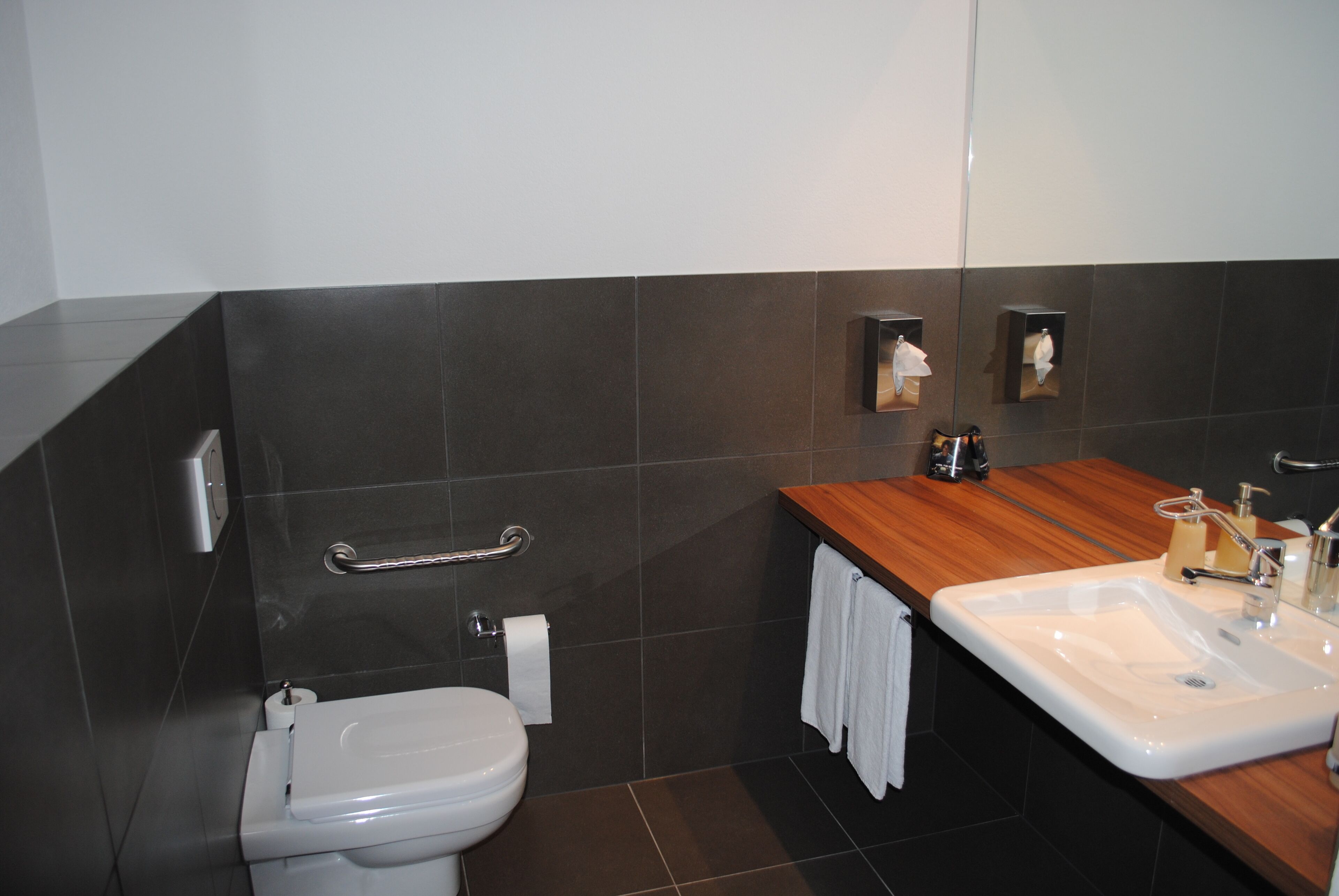 A modern bathroom with a toilet, sink, and towel rack.