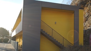 A modern building with a yellow facade and a grey section.