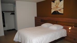 A neatly made bed with white linens in a hotel room.