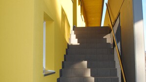 A staircase with a yellow wall on one side and a metal railing on the other.