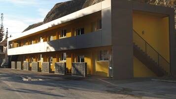 A two-story motel with a yellow facade, a staircase to the upper level, and a parking lot in front.