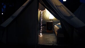 Una carpa con cama, ventilador y luces de cadena.