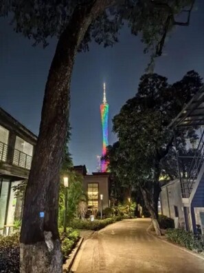 Une vue nocturne d’un immeuble doté d’une haute tour illuminée par un jeu de lumière aux couleurs de l’arc-en-ciel.