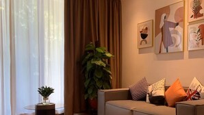 Una sala de estar moderna con una mesa de centro redonda, un sofá gris y una planta grande en maceta.