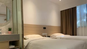 Ein Hotelzimmer mit zwei Betten, einem hölzernen Kopfteil, einem Spiegel, einem Waschbecken mit Pflanze und einem Schuhregal.