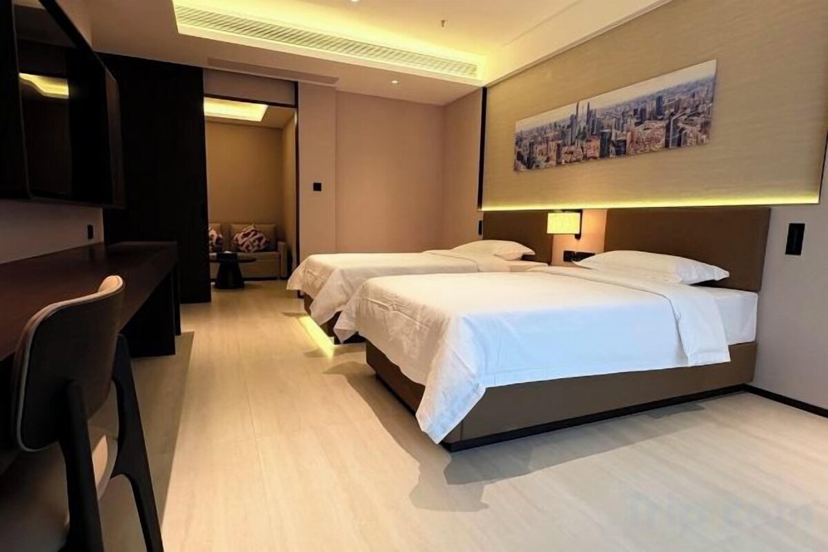 Ein Hotelzimmer mit zwei Betten, einem Schreibtisch und einem Stuhl.