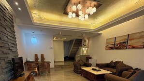 Amplia sala de estar con un mueble de madera para entretenimiento, un sofá, una mesa de centro y una escalera que conduce a un nivel superior.