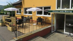 A yellow building with outdoor seating, a sign for "Haus am Berg," and a "Bilburger" restaurant sign. - Hotel Haus am Berg (Pruemzurlay)