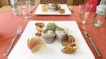 A dining table with a white plate of food, including potato wedges and a small bowl of salad.