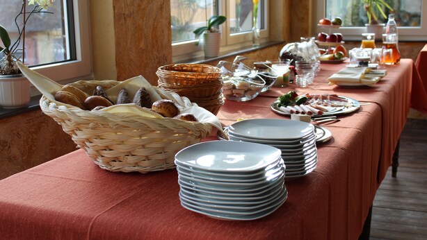 A buffet table with plates, baskets, and food items. - Hotel Haus am Berg (Pruemzurlay)