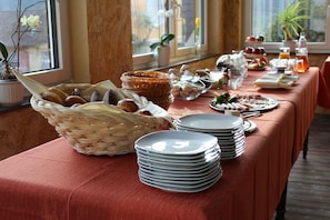 Mesa de buffet com pratos, cestas e diversos alimentos.