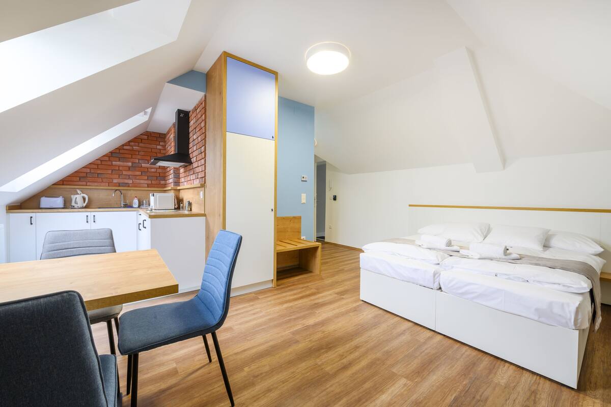 A compact, modern room with a kitchenette, a dining area, and a bed.