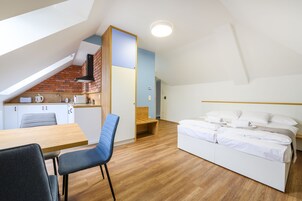 Una habitación compacta y moderna con kitchenette, comedor y cama.