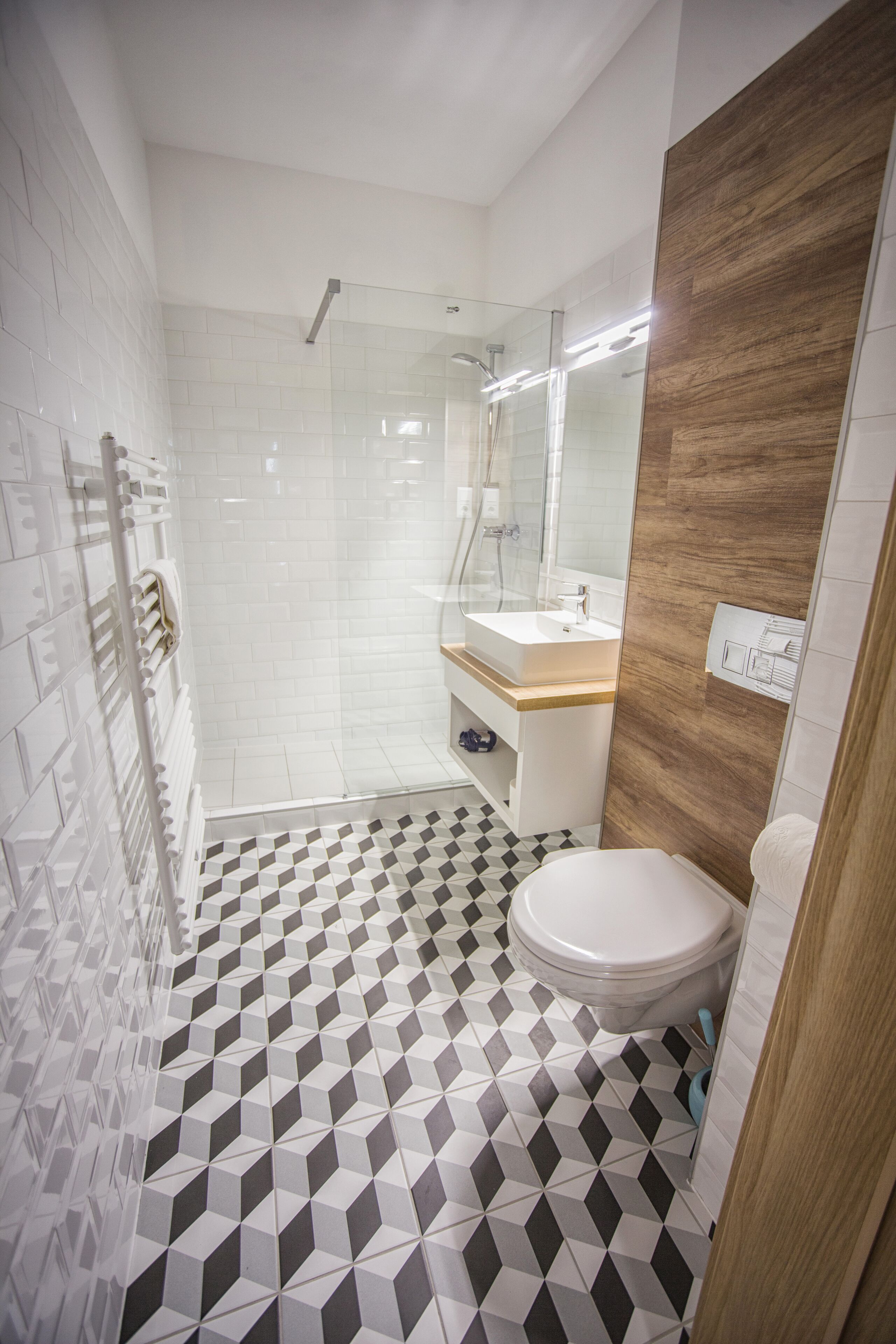 A modern bathroom with a black and white checkered floor, a white sink, and a glass shower enclosure.