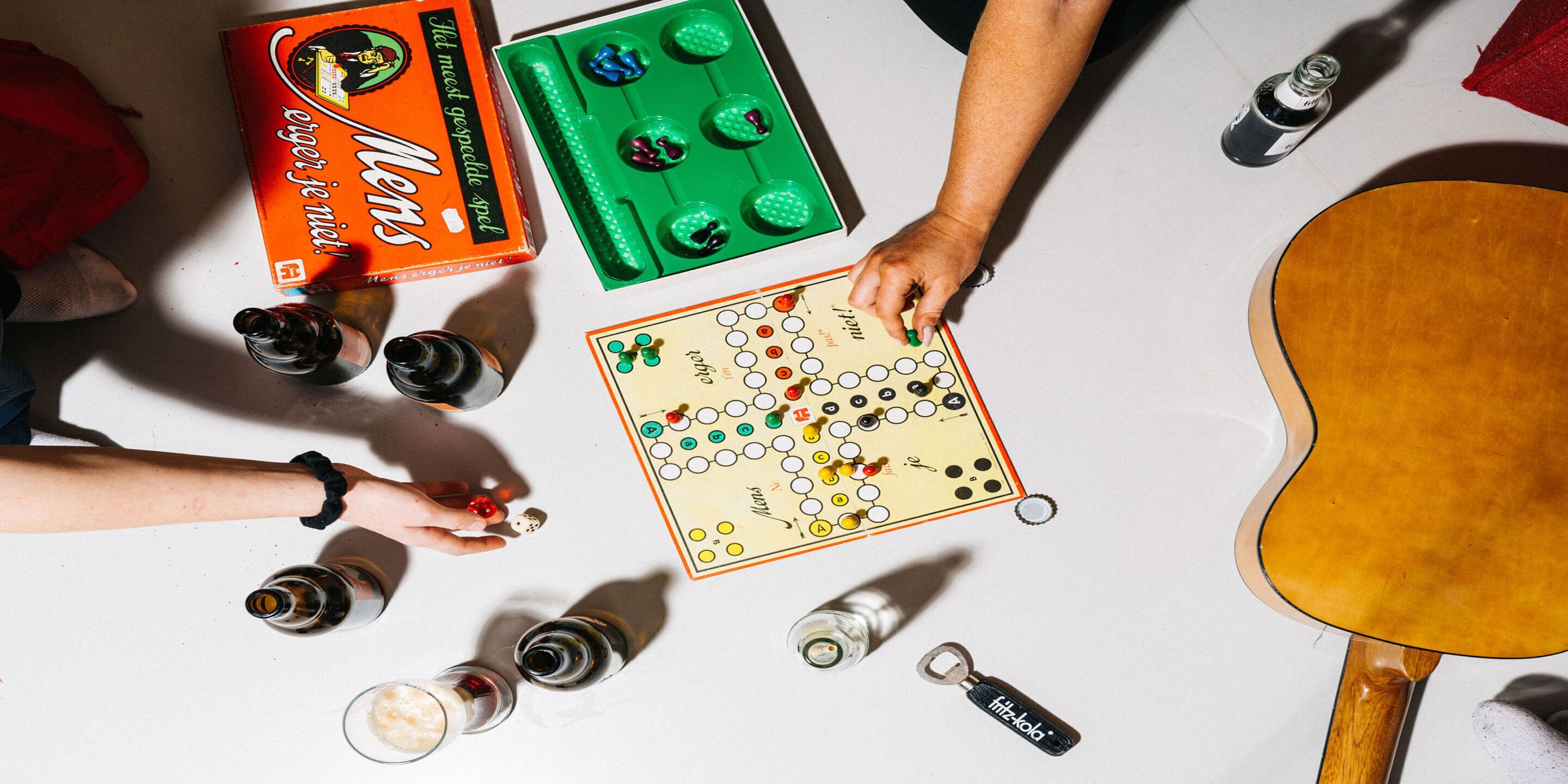 A table with a board game, bottles, and a guitar.