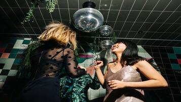 Dos personas en una habitación con suelo de baldosas, una bola de discoteca y plantas colgantes.