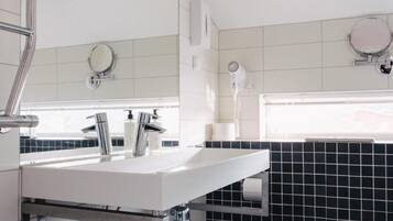 Ein modernes Badezimmer mit einem weißen Waschtisch, einer schwarzen Fliesenwand und einer weißen Toilette.
