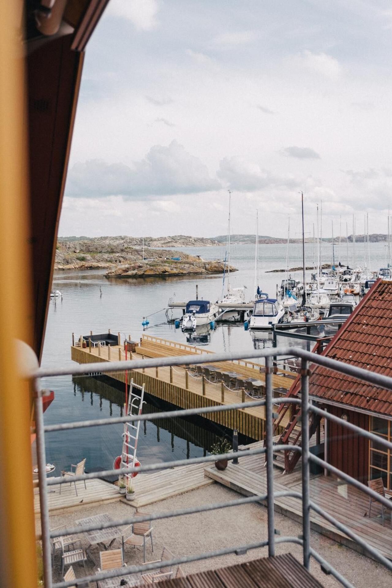 A marina with boats docked, a wooden pier, and a view of rocky terrain in the distance.