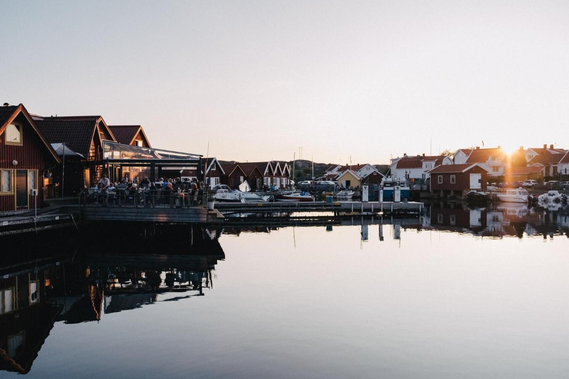 Ett område vid vattnet med byggnader, en brygga och båtar.