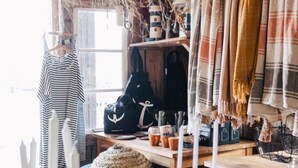 A rustic interior with wooden furniture, hanging woven lamps, and a variety of decorative items on shelves. - Björholmen Hotell & Restaurang (Klovedal)