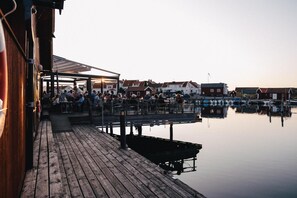 A wooden pier extending into calm water with a row of buildings in the background. - Björholmen Hotell & Restaurang (Klovedal)