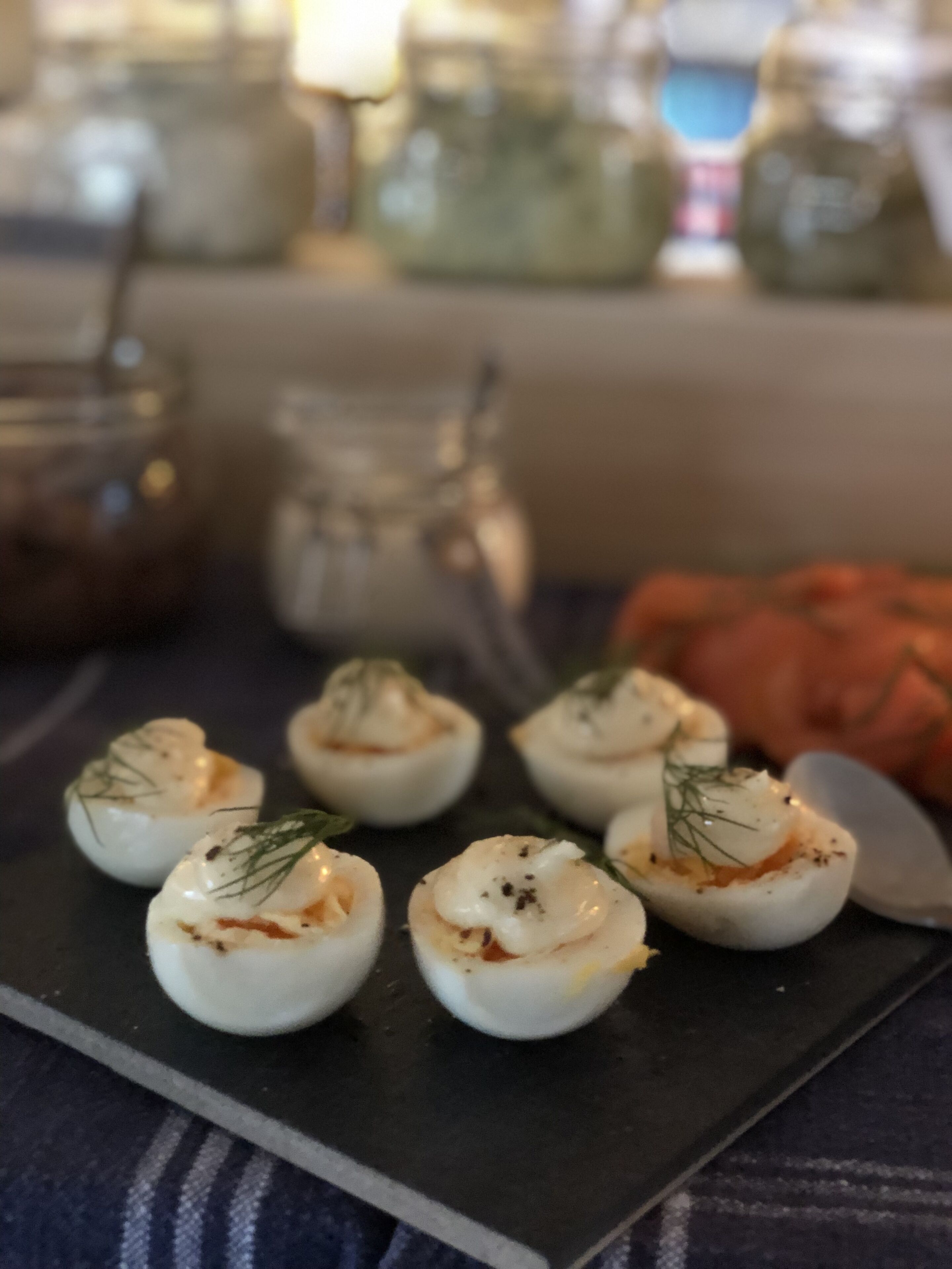 A close-up of deviled eggs garnished with dill on a dark slate board.