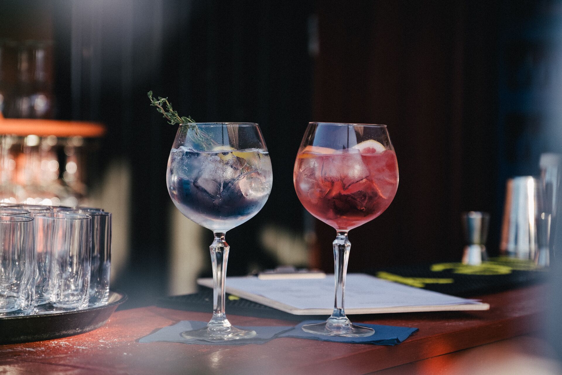 Dois copos de cocktails em um balcão de bar com fundo desfocado.