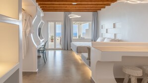 A modern hotel room with a wooden ceiling, a bed, a desk, and a view of the sea. - Sea & Stone Residence Mykonos (Mykonos)