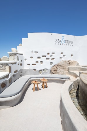 A modern outdoor seating area with a stone wall and a sign reading "SEA & STONE RESIDENCE." - Sea & Stone Residence Mykonos (Mykonos)
