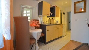 A compact kitchen with a dining area, featuring a table with a vase of flowers, a built-in oven, and a sink. - Zdenac Studio (Rovinj)