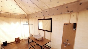 Un baño con tocador de madera, un lavabo blanco, un espejo y una zona de ducha.