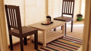A wooden table with two chairs, a tray with a cup and a thermos, and a striped rug. - Amazing Desert Camp (Jaisalmer)